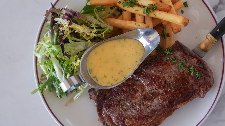 Steak frites dish with fries, salad, and boat of sauce
