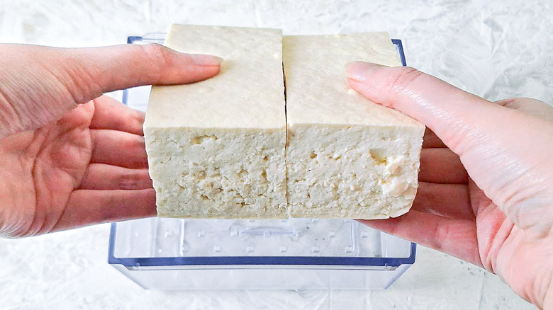 Hands placing tofu in press