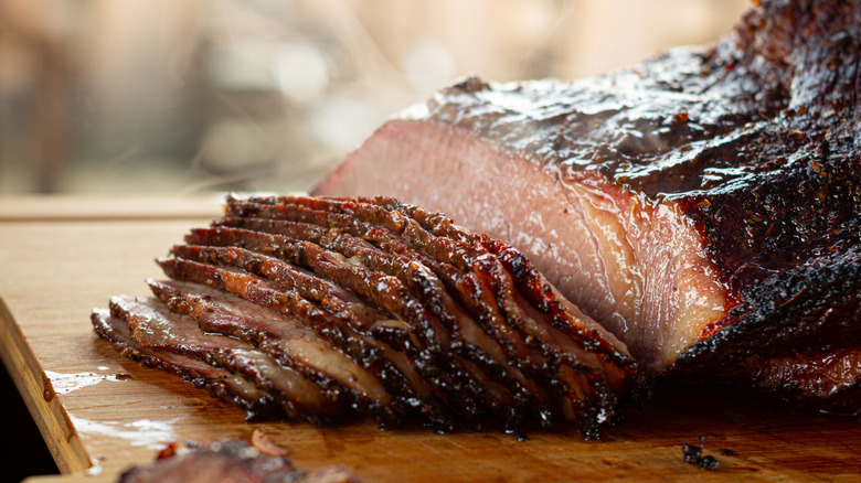 Slices of beef brisket stacked on a wooden cutting board