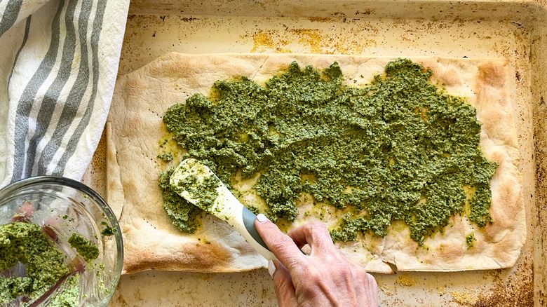 spreading pesto on flatbread