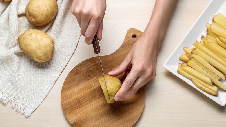 person cutting a potato