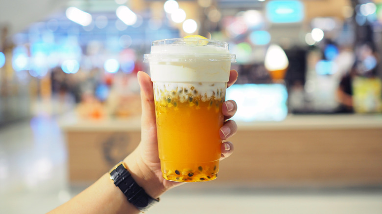 person holding passionfruit cheese tea