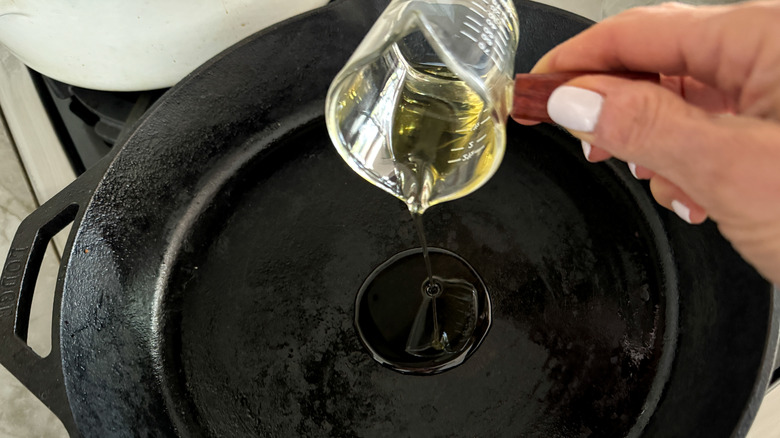 hand adding oil to pan