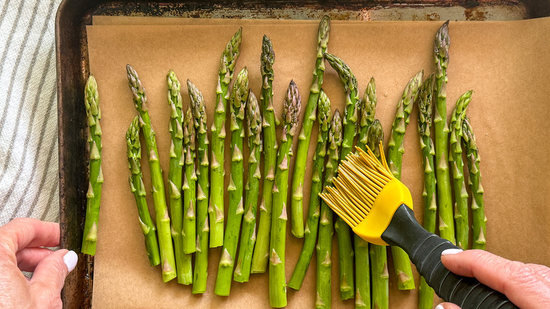 hand brushing asparagus with oil