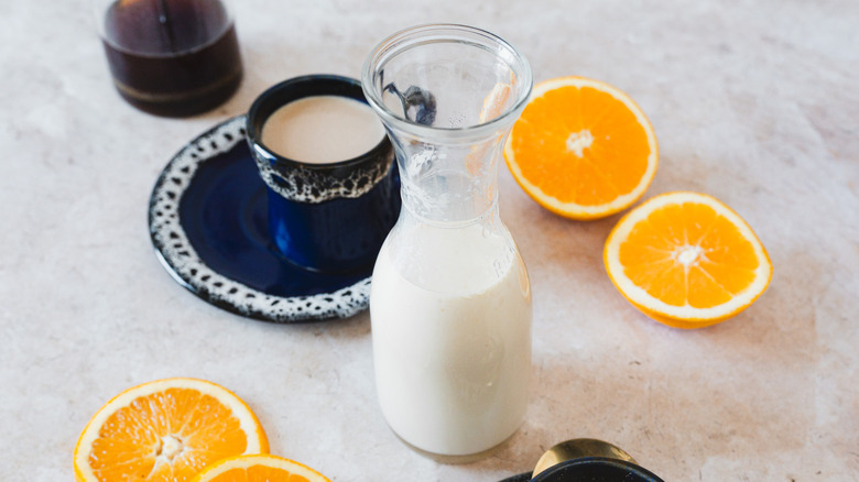 Bottle of creamer next to coffee and oranges