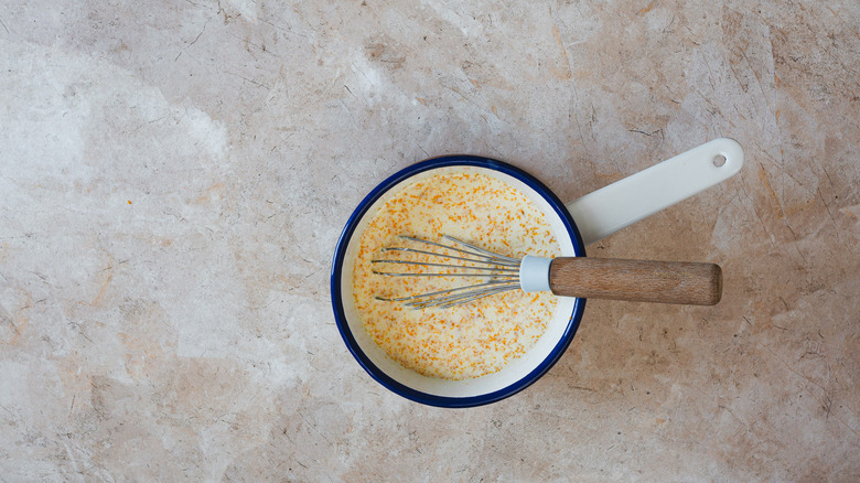 Saucepan with orange zest and whisk