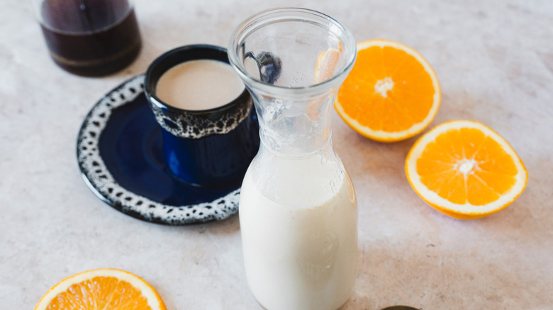 Bottle of creamer next to coffee and oranges