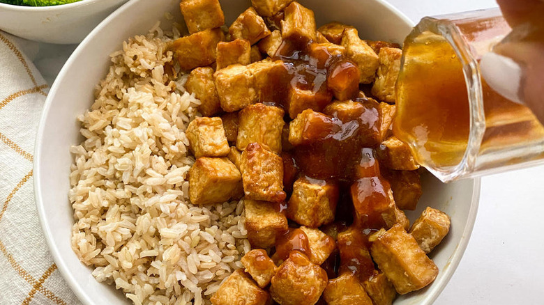 pouring teriyaki sauce onto tofu