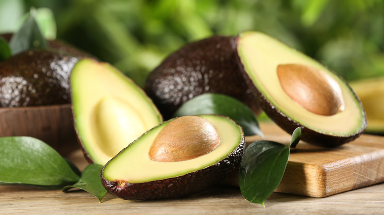 Ripe avocado halves on wooden table