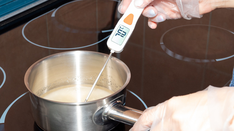 hand measuring temperature of boiled sugar