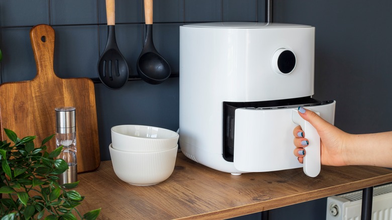 Person pulling out air fryer basket