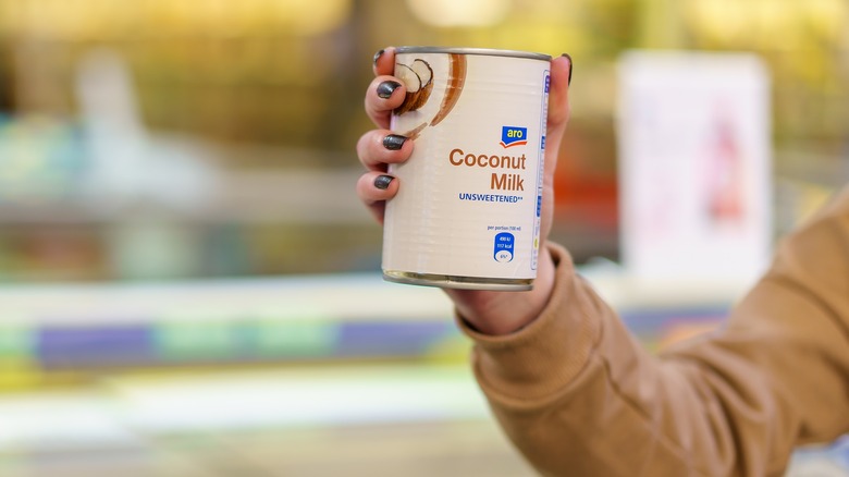 A person holding unsweetened coconut milk in a can