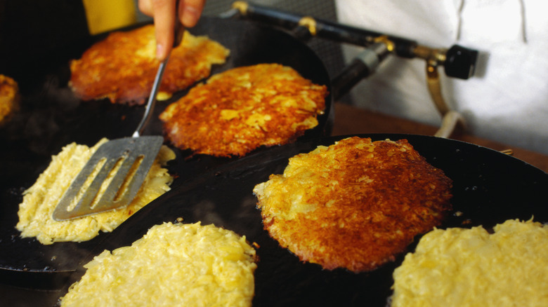 many hash browns on pans with a spatula