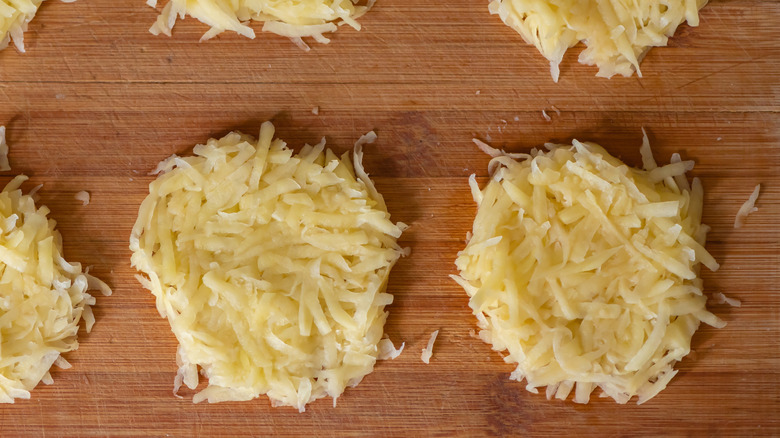 raw grated potato patties on wooden cutting board