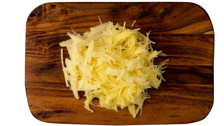 raw grated potato on wooden cutting board