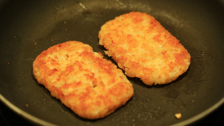 hash brown patties heating in a skillet