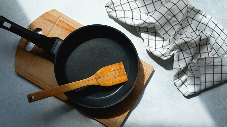 cast iron frying pan with wooden spoon on board