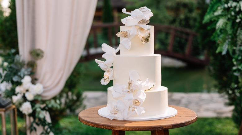 white minimalist wedding cake surrounded by greenery