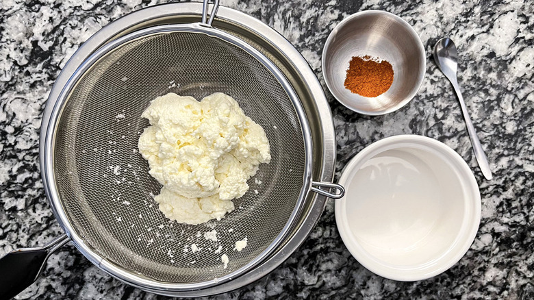 straining cheese curds over pot