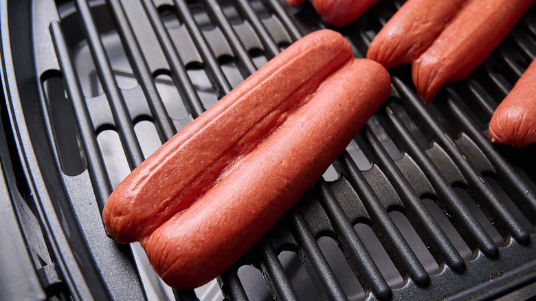 butterflied hot dogs cooking on grill