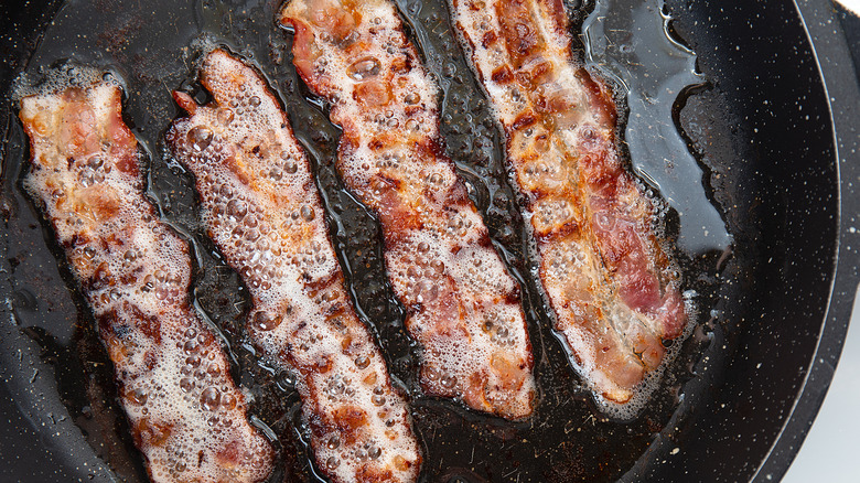 Bacon cooking surrounded by grease