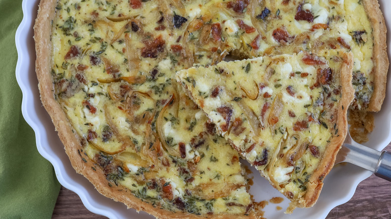 a slice of quiche being cut out of a whole quiche