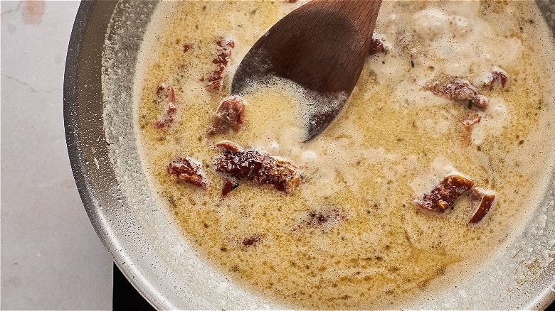 stirring sauce in skillet with spoon