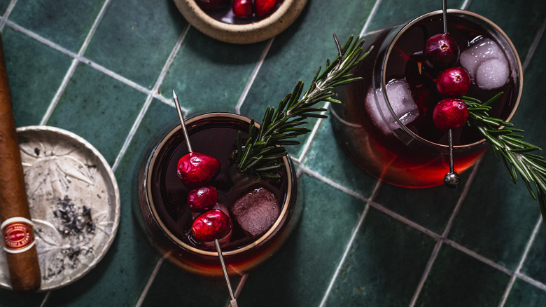 Overhead view of two cocktails with a cigar and cranberries