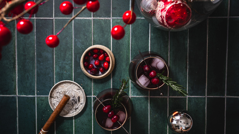 A cocktail with cranberries and a rosemary sprig