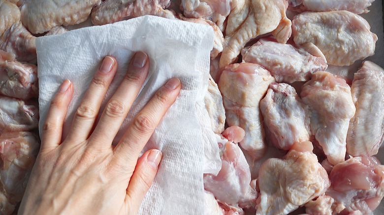 hand patting chicken wings dry