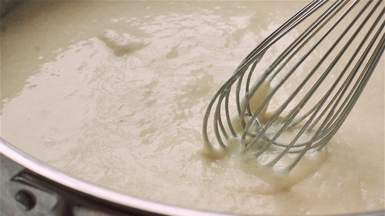 whisking thick cheese sauce