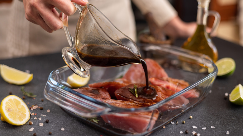 Hand pouring marinade over steak