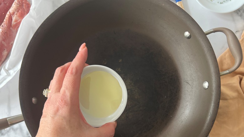 hand putting oil in pan