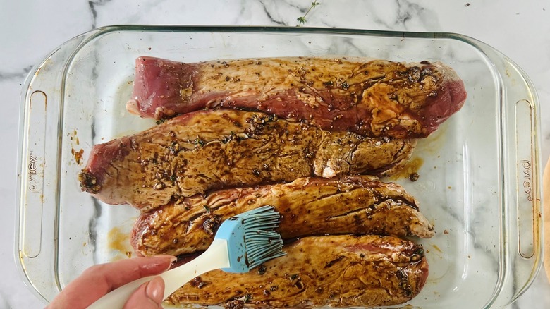 fingers brushing glaze on pork