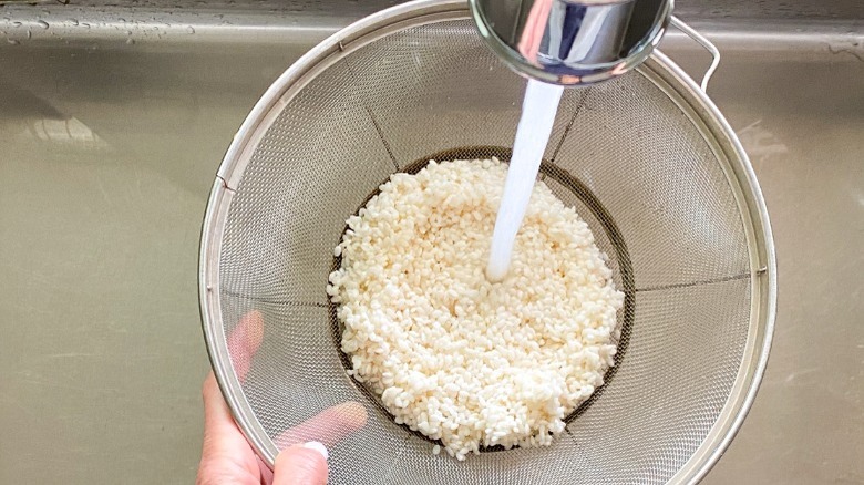 rice in colander under water stream