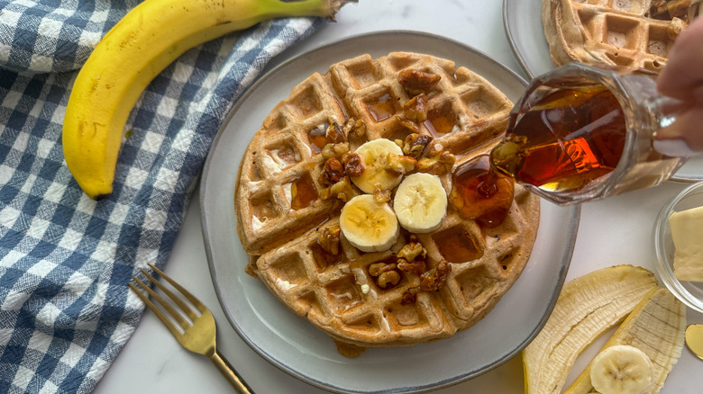 hand pouring syrup on waffle