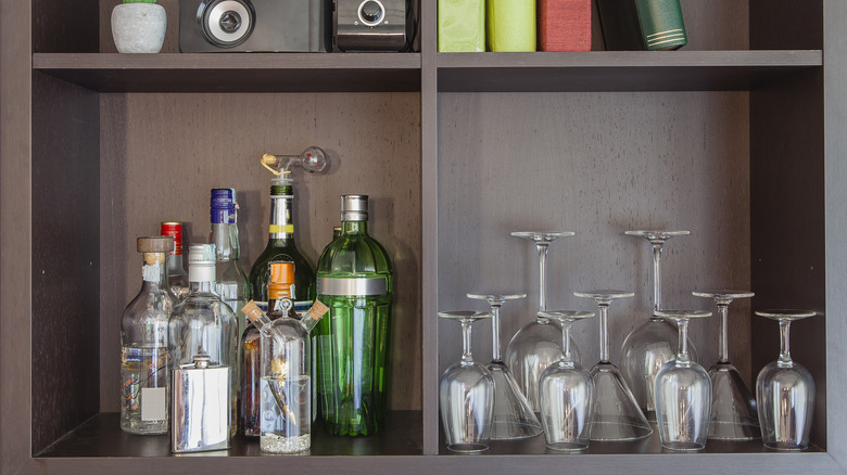 A simple liquor cabinet with a few bottles on one side and glasses on the other