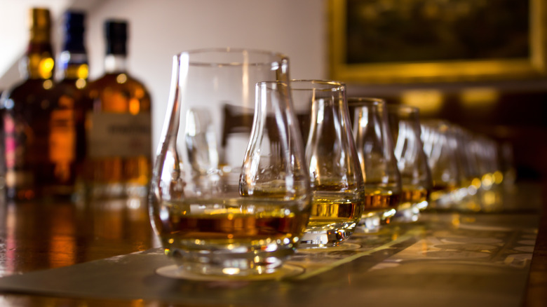 Spirit glasses set up for a tasting event with bottles in the background