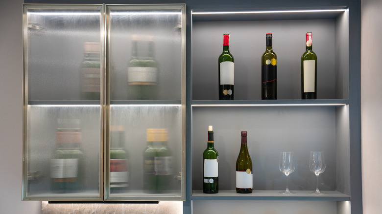 A sleek and modern liquor cainet with a few bottles and glasses inside