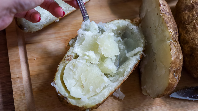 the inside of potatoes being scooped out with a spoon