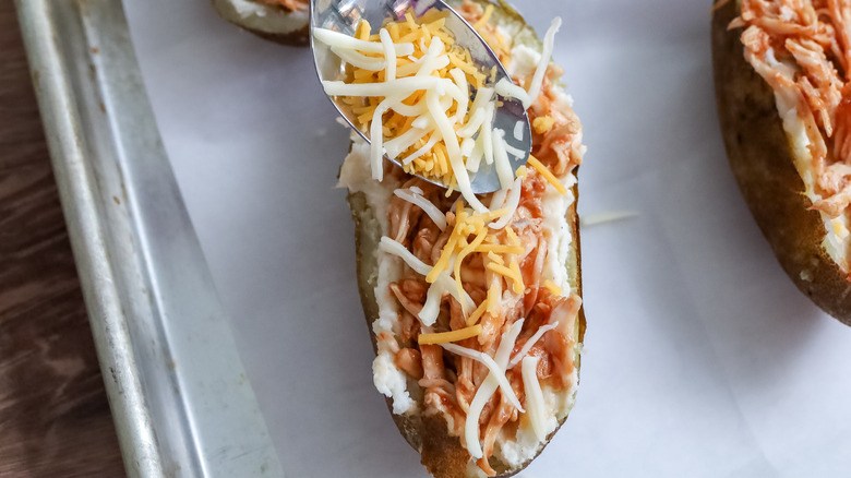 cheese being spooned onto potatoes