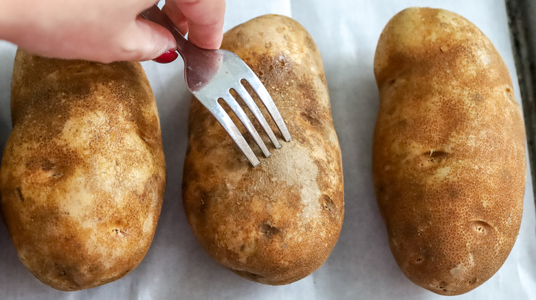 holes being poked in potatoes with a fork