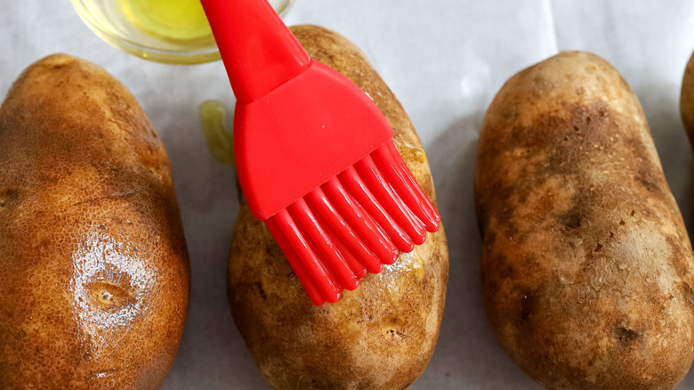 potatoes being brushed with olive oil