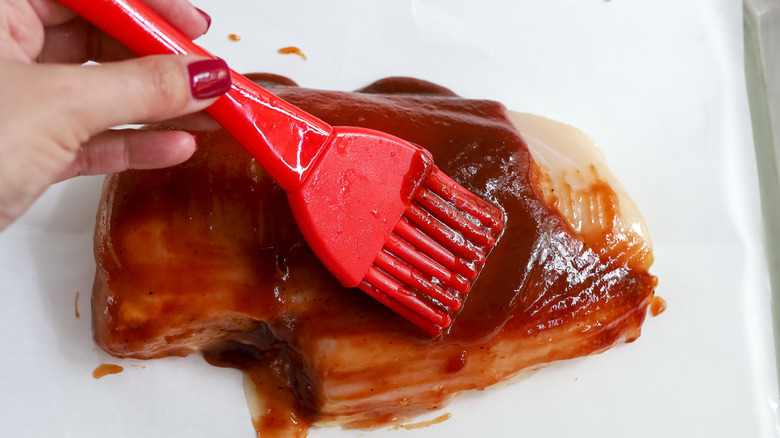 chicken being brushed with barbecue sauce