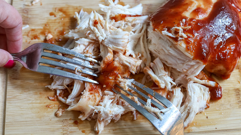 barbecue chicken being shredded with forks