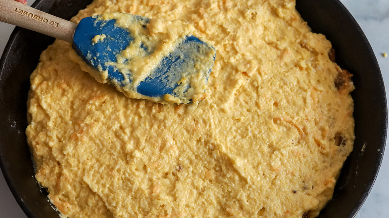 spreading cornbread batter in cast iron skillet