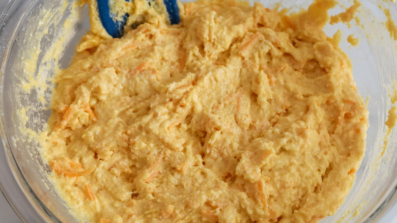 stirring cheesy cornbread batter in bowl