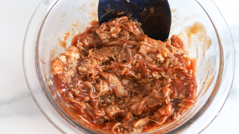 stirring pulled pork with barbecue sauce
