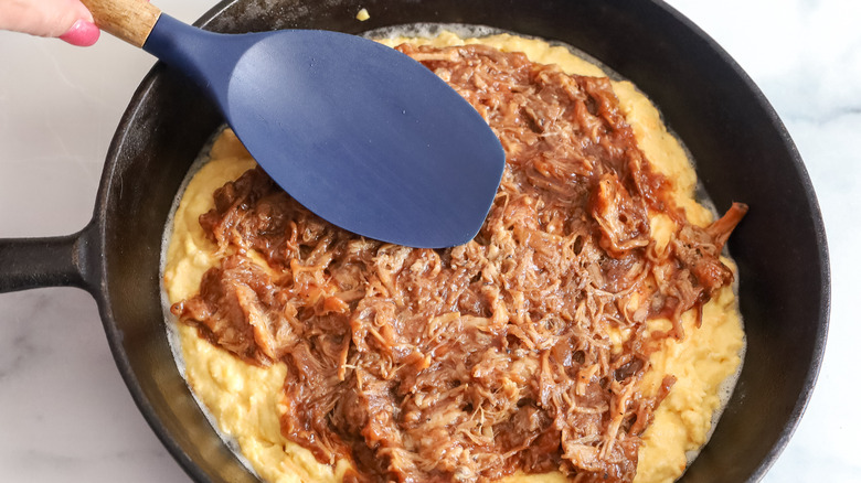 spreading bbq pulled pork over cornbread batter
