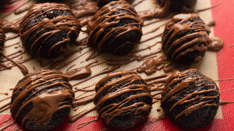 Oreo dough balls drizzled in chocolate on a tray